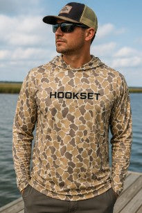 Angler wearing HOOKSET Timber Duck camouflage fishing hoodie featuring UPF 50 sun protection and lightweight performance fabric