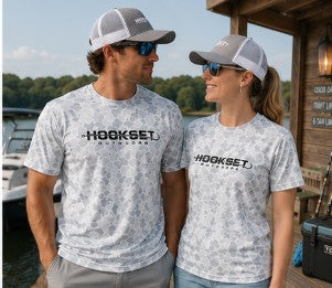 Man and woman wearing Hookset Outdoors Blue Ice camouflage short sleeve performance fishing shirts at a lakeside dock.