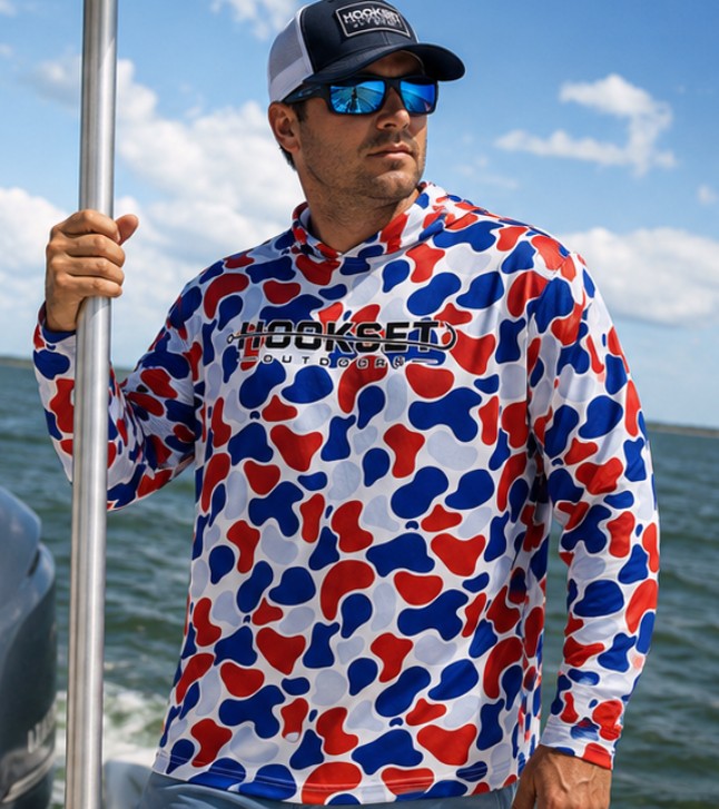 Man wearing Hookset Freedom UPF 50 fishing hoodie on a boat in open water.