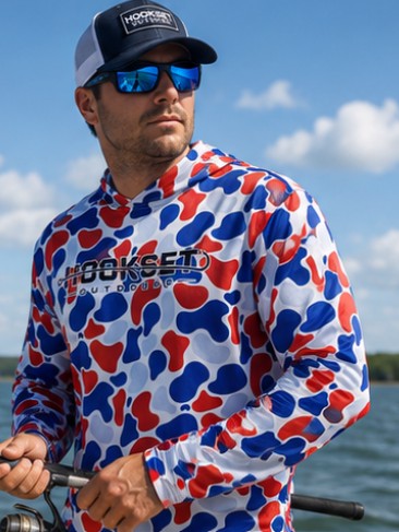 Man fishing on a boat wearing Hookset Freedom UPF 50 fishing hoodie with patriotic red white and blue duck camo pattern.